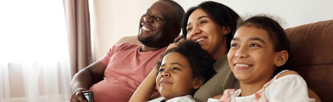 Foto de uma família com pai, mãe e dois filhos de pele escura para ilustrar o post sobre membros da família em inglês