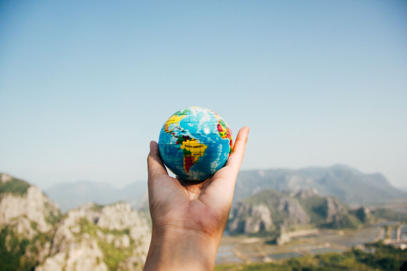 Foto de uma mão segurando um globo representando o post sobre cursos de inglês para viagens